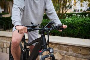 Close-up of a man cyclist riding an electric bike, bicycle in the city street. Bike sharing city service. Copy ad space photo