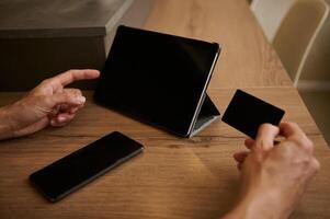 Man using a digital tablet with mockup touch screen and black empty credit card, shopping online on internet web sites photo