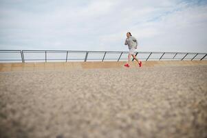 Full size portrait athletic man running in the city. Copy advertising space. Running. Jogging. Sprinting. Cardio workout photo