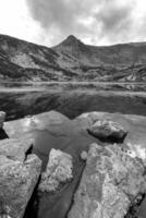 paisaje de día de belleza en el lago de montaña con rocas en el frente. vista vertical foto