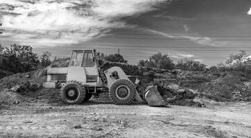 un excavadora o cargador se mueve el tierra durante el construcción. pesado equipo para movimiento de tierras foto