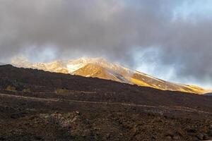 View of the volcanic rocks and volcano Etna in Sicily from a road photo