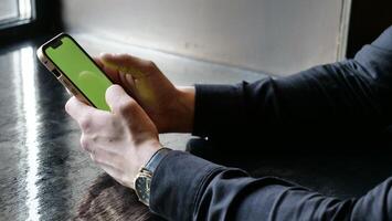 de cerca teléfono inteligente con verde pantalla en de los hombres manos. un empresario rollos el teléfono con croma llave en el oficina. foto