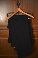 Pants on a wooden hanger. Folded blue trousers. photo