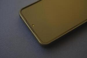 A black smartphone on a blue background. A new gadget. A smartphone with a protective film and a case. photo