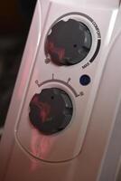 Round switches on a white radiator. The control panel. photo