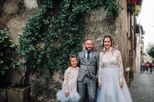 A happy young family walks through the old town of Sirmione in Italy.Stylish family in Italy on a walk photo