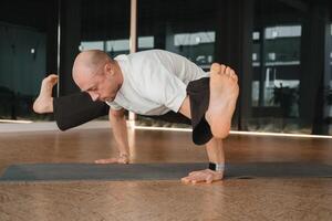 un atlético joven hombre lo hace ejercicios en el aptitud habitación. un profesional chico lo hace yoga en el gimnasio foto