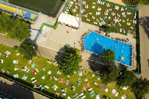 Top view of an outdoor place for people to relax where there is a swimming pool and a lot of sun beds photo