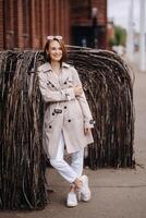 A happy stylish girl in a gray coat walks around the city photo