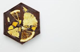 hecho a mano oscuro chocolate bar con un seco Fruta Adición - rebanadas de naranja, mango, piña. hecho en casa chocolate ladrar en forma de panal. parte superior vista. aislado en blanco antecedentes. Copiar espacio foto