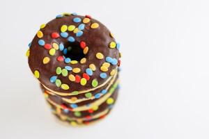 A stack of doughnuts glazed with chocolate and colorful smarties. Pile of 5 donuts isolated on a white background. Top view. Copy space photo