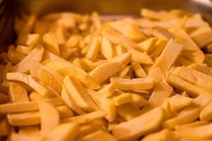 Yummy French fries  as background. Potato chips on the counter at the street market. Selective focus. Side view. Bokeh. photo