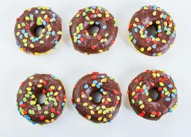 Set of six tasty chocolate donuts with smarties on white background. 6 Doughnut decorated with colorful nibble on top. Birthday party.  Hanukkah celebration concept. Isolated. Top view photo