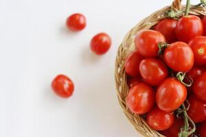 Many red cherry tomatoes with sepals in the basket isolated on the white background.  Tomato pile. Ripe and fresh organic vegetables harvested from local farmers. Clipping path. Top view. Copy space. photo