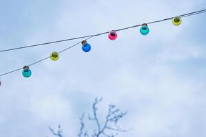 Christmas garland light bulbs on cloudy sky background. Wedding ceremony decoration. Tree branches without leaves. Backdrop, wallpaper. Minimalistic conceptual simple graphic design idea. Copy space photo