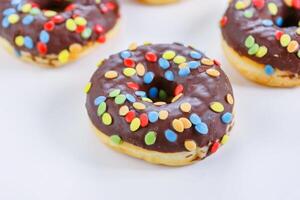 Set of Brown chocolate donut decorated with smarties isolated on white background side view. Fried dough confection, dessert food, sweet snack with chocolate glazing and candies. Selective focus photo