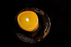 Lit candle on the wooden table. Burning candle in the candleholder. Burning light. hot fire. Cozy atmosphere. Copy Space. Backlight from the window. Top view. Selective focus. photo