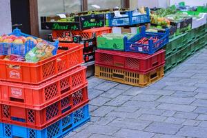 Ochsenfurt, Germany - April, 27th, 2023. Street food market in old German village in Lower Franconia. Red, blue, green plastic and carton boxes with fresh fruits and vegetables. Selective focus photo