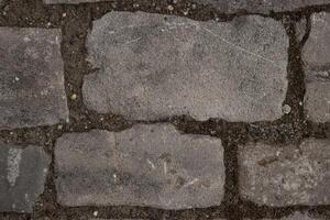 Close-up of the paving stone pavement texture. Cobblestone top view. Old stone sidewalk. Cobble stone road, retro cobble texture. Brick wall. Wallpaper,  background photo