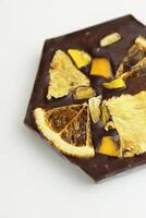 hecho a mano oscuro chocolate bar con un seco Fruta Adición - rebanadas de naranja, mango, piña. hecho en casa chocolate ladrar en forma de panal. parte superior vista. aislado en blanco antecedentes. Copiar espacio foto