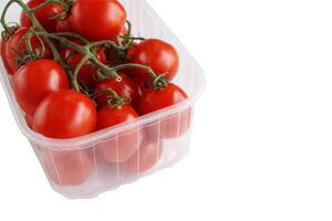 Plastic tray with red cherry tomatoes with sepals isolated on the white background. Tomato pile. Ripe and fresh organic vegetables harvested from local farmers. Clipping path. Top view. Copy space. photo