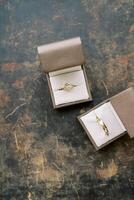 Wedding rings in boxes lie on a scratched table. Top view photo