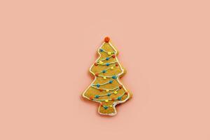 Cookie in the shape of a colorful Christmas tree on a pink background photo