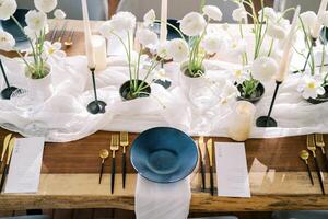Black plates stand on white napkins near the menu and gold cutlery on the festive table photo