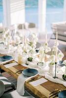 Black plates on white napkins stand next to gold cutlery and menus on a holiday table with white flowers photo