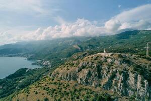 Church of St. Sava on a rocky mountain overlooking the green mountain range above the Bay of Kotor. Montenegro. Drone photo