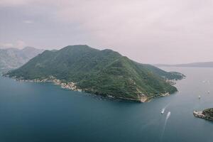 Yachts sail along the Bay of Kotor past the green mountain range. Aerial view photo