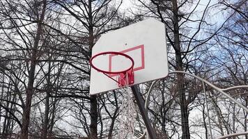 A basketball hoop in the yard with a torn net. Throwing the ball into the hoop video