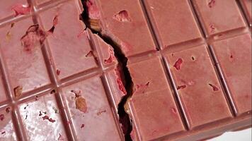 A breaking bar of pink ruby chocolate with freeze-dried strawberries and almonds close-up, . A healthy dessert based on berries and nuts video