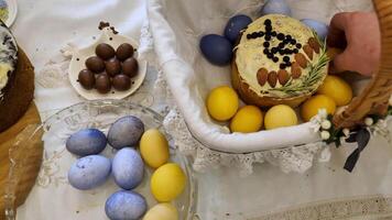 tradicional Pascua de Resurrección pan, rodeado por vistoso Pascua de Resurrección huevos. el kulich es adornado con intrincado Formación de hielo y coronado con aplastada nueces , mientras el huevos son teñido en vibrante sombras de azul y amarillo. video