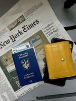 Ukrainian Refugee Passpart, money euro, popular newspaper The New The New York Times about Ukraine and Yellow Wallet. Flatley travel close up , vertical photo