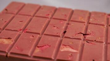 A bar of pink ruby chocolate with freeze-dried strawberries and almonds close-up. A healthy dessert based on berries and nuts video