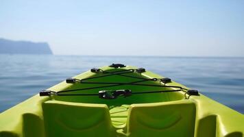 Sea water surface. Camera flies over the calm azure sea with green kayak boat on foreground. Nobody. Holiday recreation concept. Abstract nautical summer ocean nature. Slow motion. Close up video