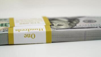 stack of bank bundles with US dollars on a white background. Close-up shot of new, freshly printed hundred-dollar bills rotating on a table. cash flow, business investment, or big money concepts. video