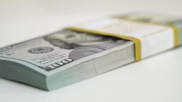 stack of bank bundles with US dollars on a white background. Close-up shot of new, freshly printed hundred-dollar bills rotating on a table. cash flow, business investment, or big money concepts. video