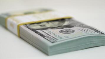 stack of bank bundles with US dollars on a white background. Close-up shot of new, freshly printed hundred-dollar bills rotating on a table. cash flow, business investment, or big money concepts. video