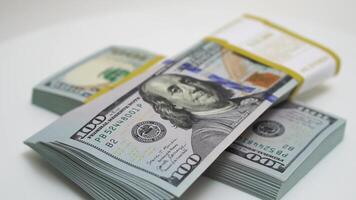 stack of bank bundles with US dollars on a white background. Close-up shot of new, freshly printed hundred-dollar bills rotating on a table. cash flow, business investment, or big money concepts. video