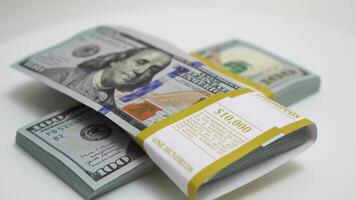 stack of bank bundles with US dollars on a white background. Close-up shot of new, freshly printed hundred-dollar bills rotating on a table. cash flow, business investment, or big money concepts. video