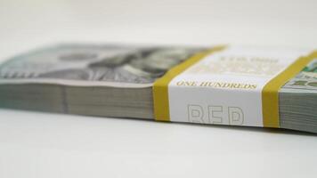 stack of bank bundles with US dollars on a white background. Close-up shot of new, freshly printed hundred-dollar bills rotating on a table. cash flow, business investment, or big money concepts. video