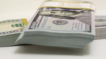 stack of bank bundles with US dollars on a white background. Close-up shot of new, freshly printed hundred-dollar bills rotating on a table. cash flow, business investment, or big money concepts. video