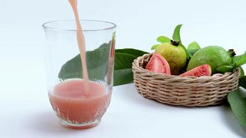 Pouring fresh guava and red guava juice in a woven bamboo basket with green leaves video