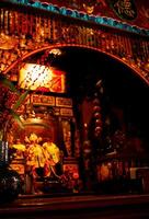 The prayer room contains a statue of a Chinese God with burning red incense photo