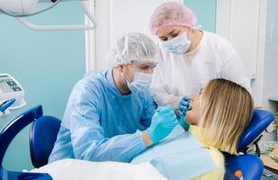 The patient smiles in the dentist's chair in a protective mask and instrument before treatment in the dental office photo