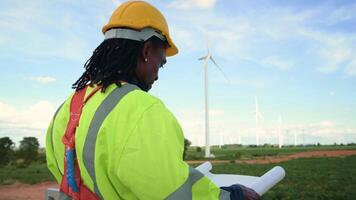 Smart engineer with protective helmet holding the blueprint working at electrical turbines field video