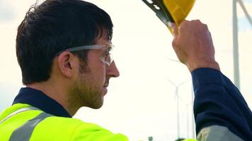 un inteligente ingeniero es poniendo un protector casco en cabeza a eléctrico turbinas campo video